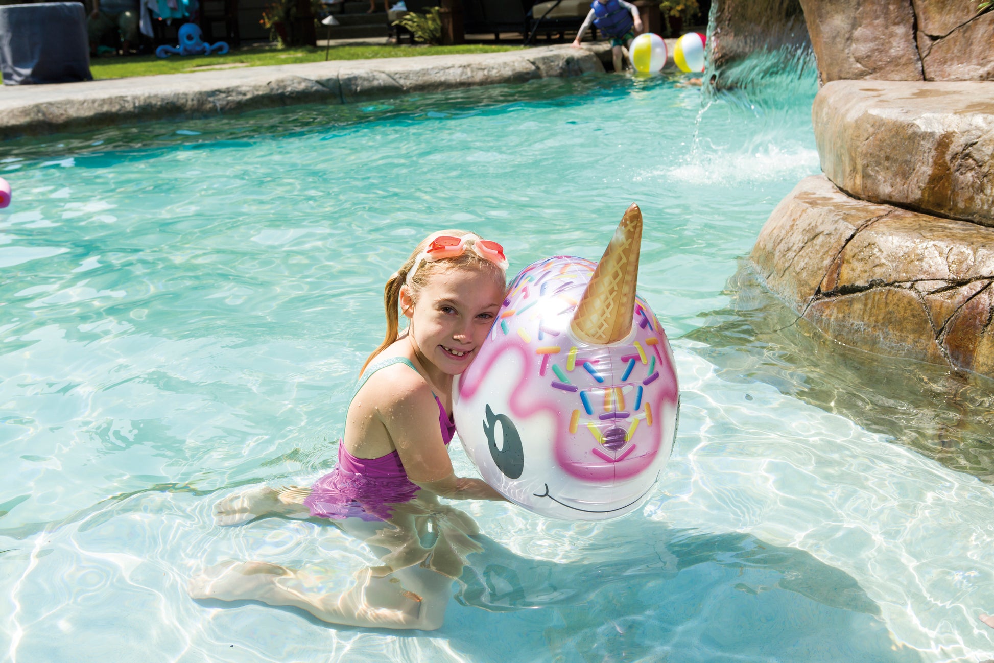 Girl holding Bobbin Buddies Narwhal in front of a pool
