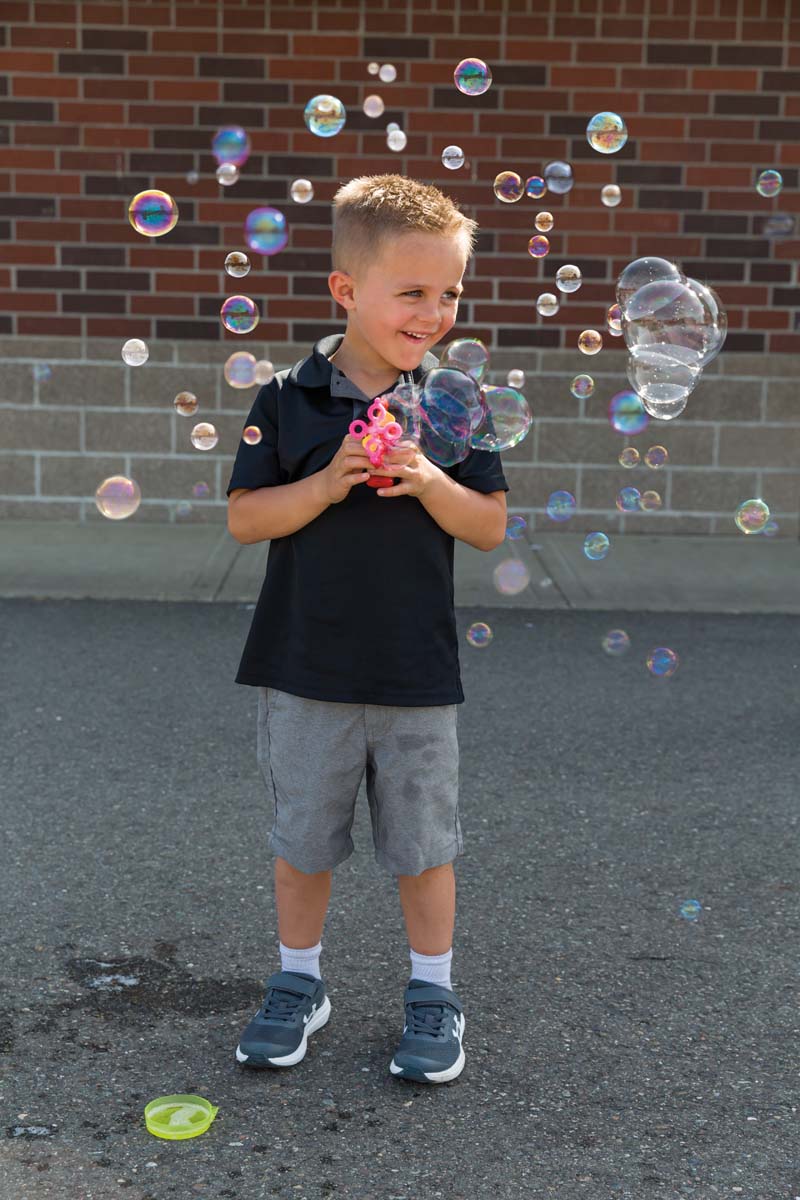 Young boy blowing bubbles outside with Turbo Bubble Blower.